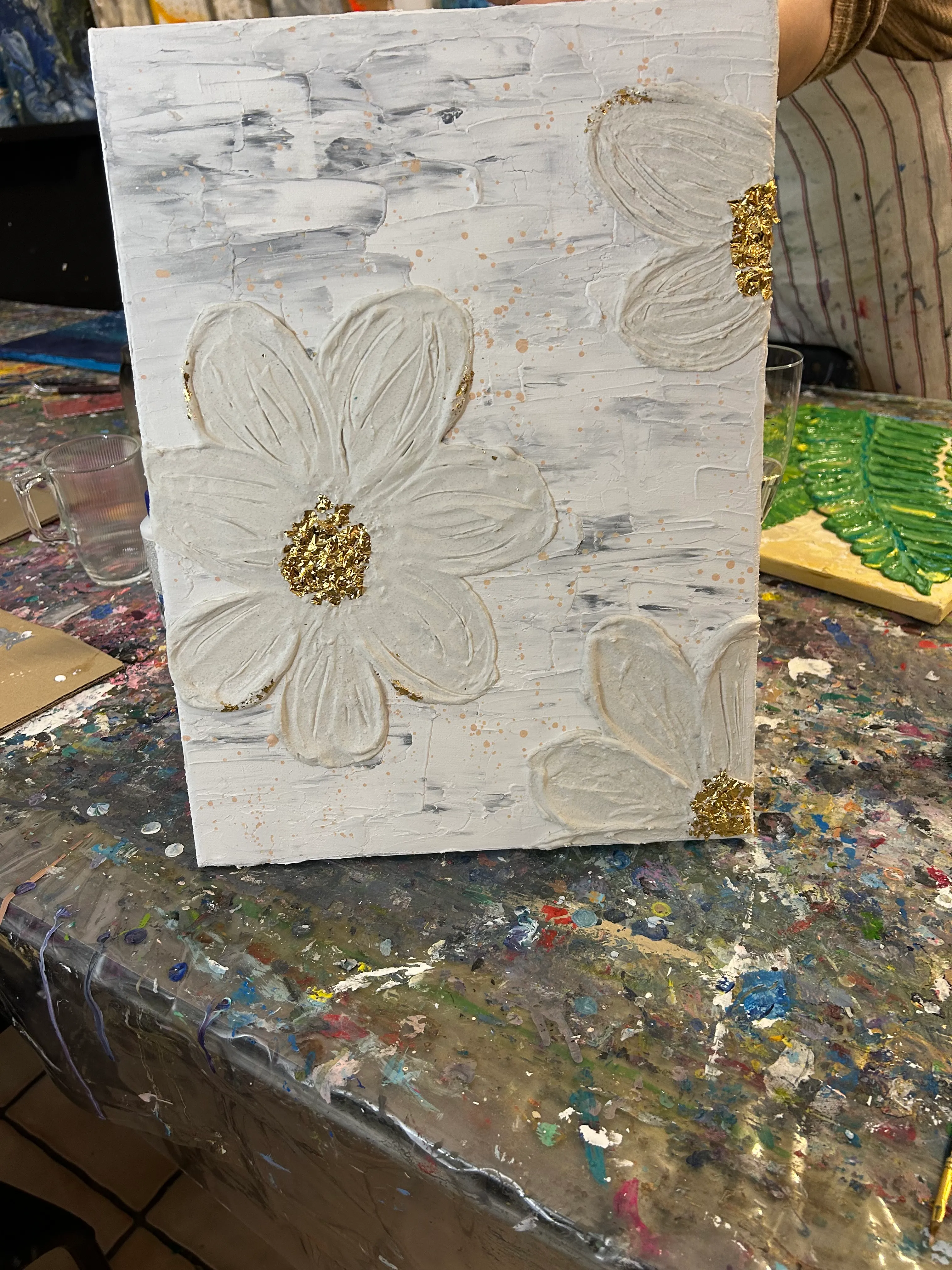 Texturiertes weißes Blumenbild auf unordentlichem Tisch.