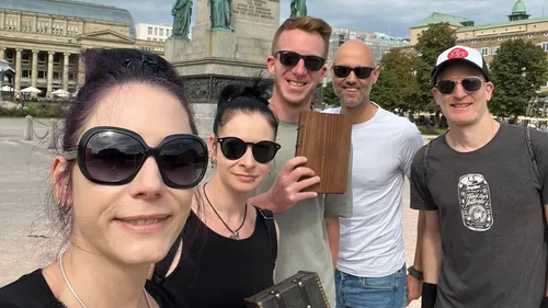 Gruppe von fünf Personen lächelt im Freien.