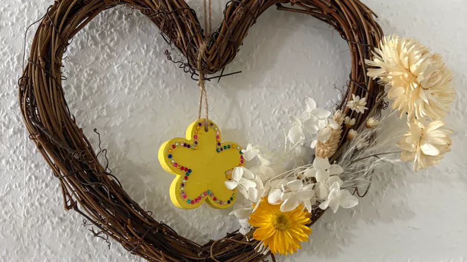 Heart-shaped wreath with flowers on wall.