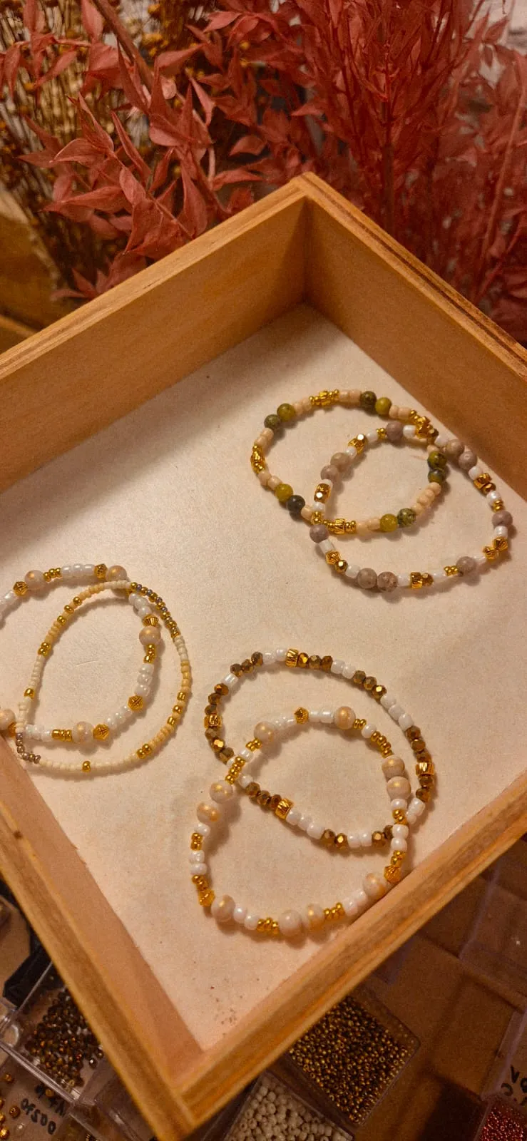 Beaded bracelets in a wooden box, with plants.