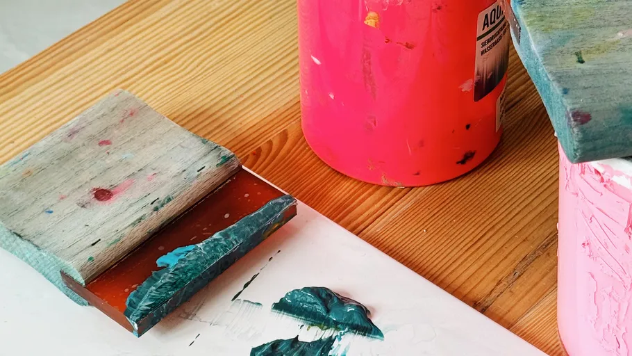 Rakels und Farbbehälter auf Holztisch.