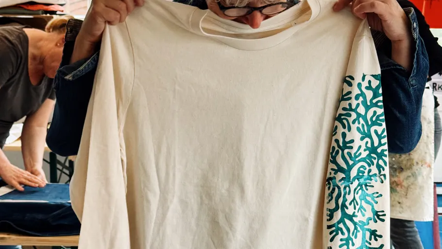 Person hält ein Hemd mit Korallendesign.