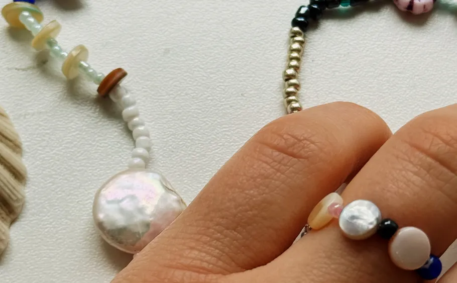 Hand wears colorful beaded rings on table.