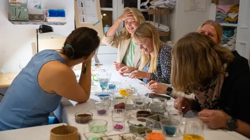 Women crafting jewelry at a table indoors.