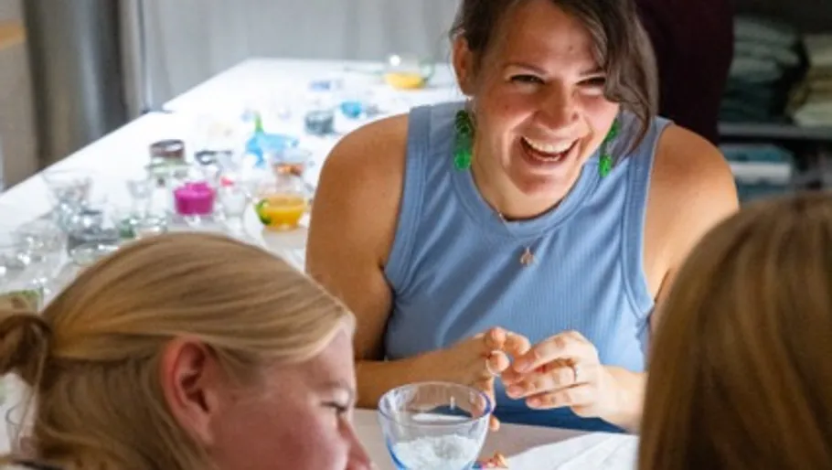 Woman laughing at table with crafts.