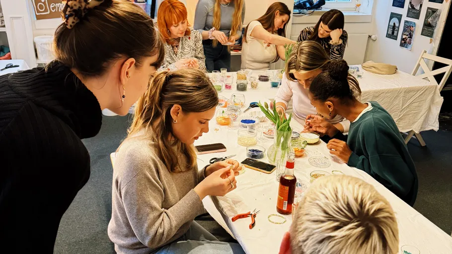 Personen basteln Schmuck an einem Tisch drinnen.