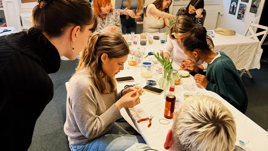 People crafting bracelets around a table.