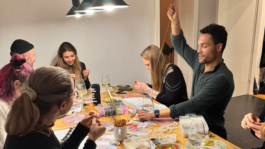 Gruppe bastelt Schmuck an Tisch im Innenraum.