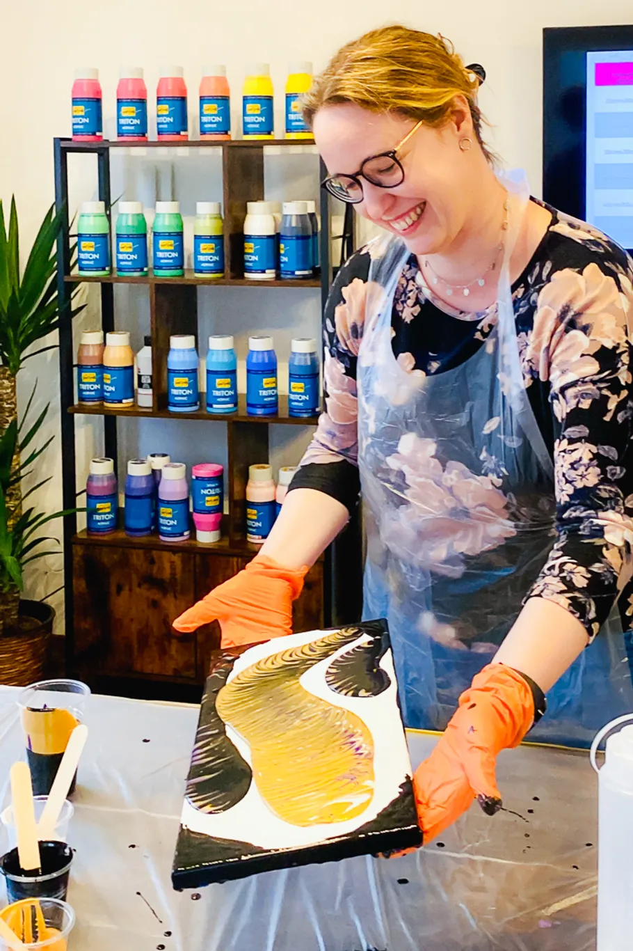 Woman painting with colorful bottles nearby.