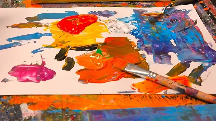 Colorful abstract painting with brushes nearby.