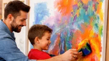 Mann und Kind malen bunte abstrakte Kunst.