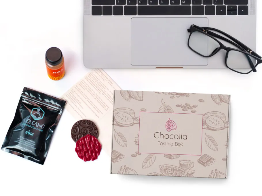 Chocolate tasting box is next to a laptop and glasses.