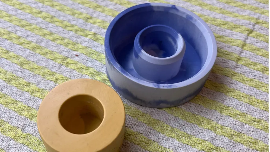 Two plastic molds on striped fabric.