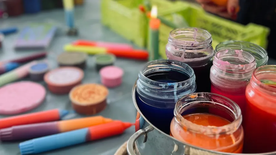 Colorful candle wax in jars on crafting table.