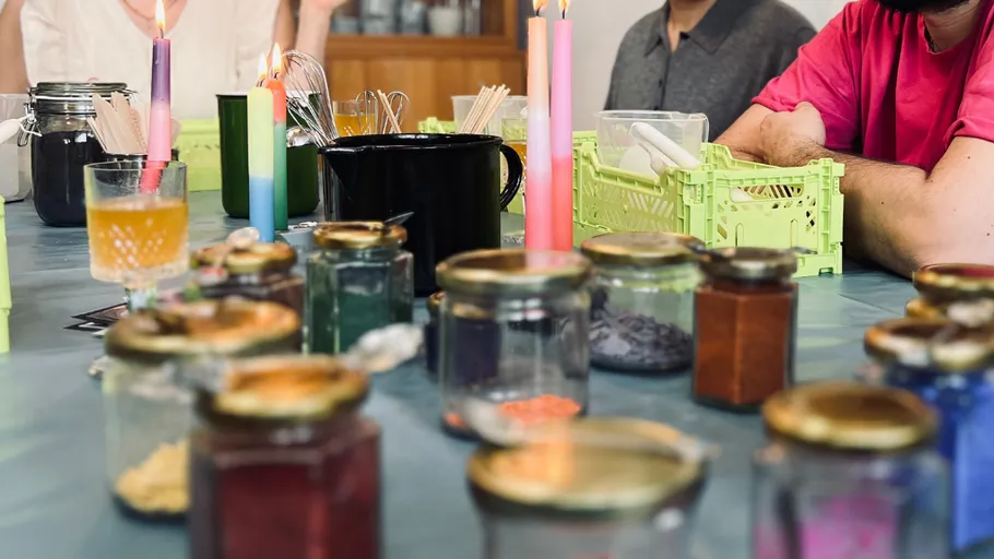 Jars and candles on table, people crafting.