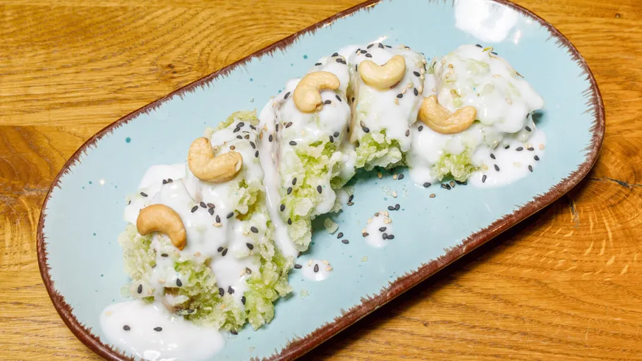 Green rice dessert with nuts on blue plate.