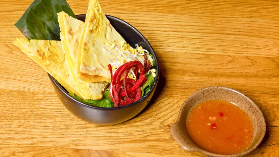 Schüssel mit Pfannkuchen und Sauce auf Tisch.