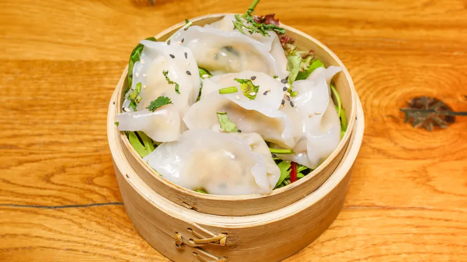 Gedämpfte Teigtaschen im Bambuskörbchen auf Tisch.