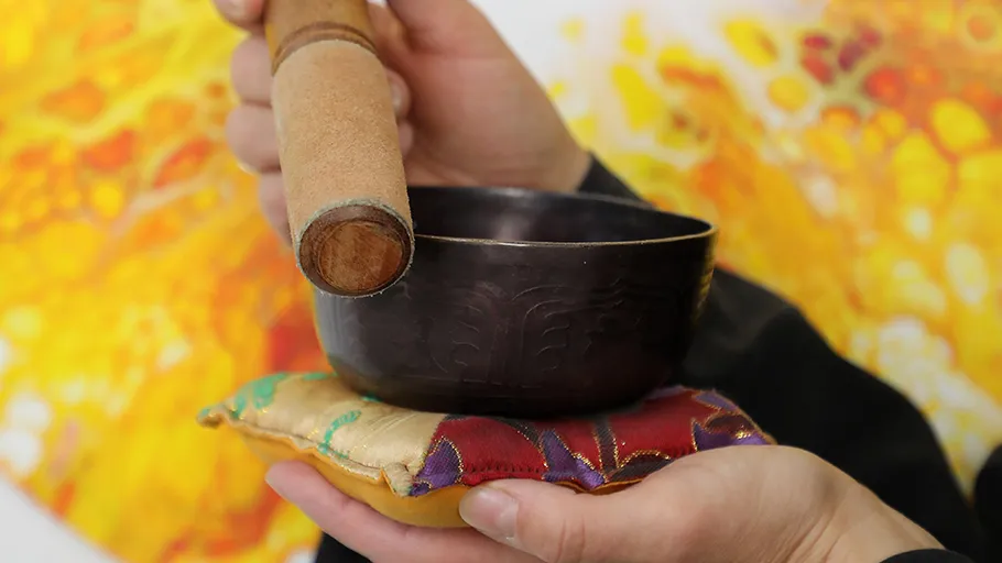 Hands holding singing bowl and mallet.