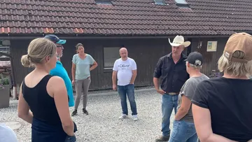 Group of people standing outside a barn.