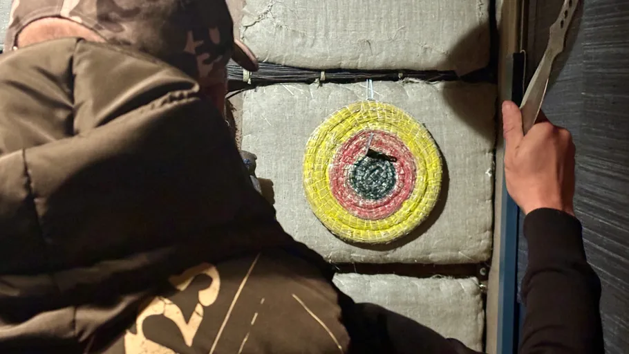 Person hält Messer vor Zielscheibe.