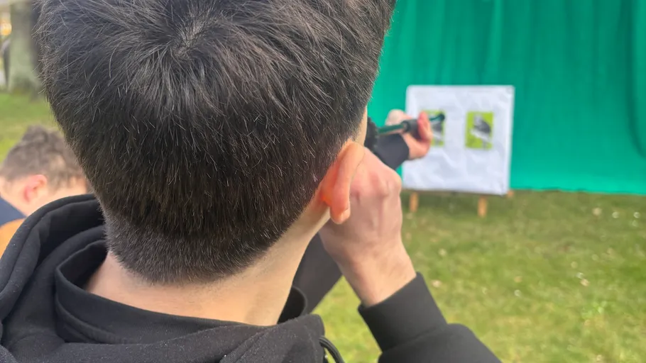 Person aims slingshot at target outdoors.