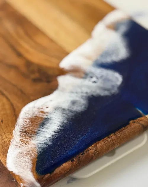 Holzbrett mit Harz-Ozeanwellen-Design.