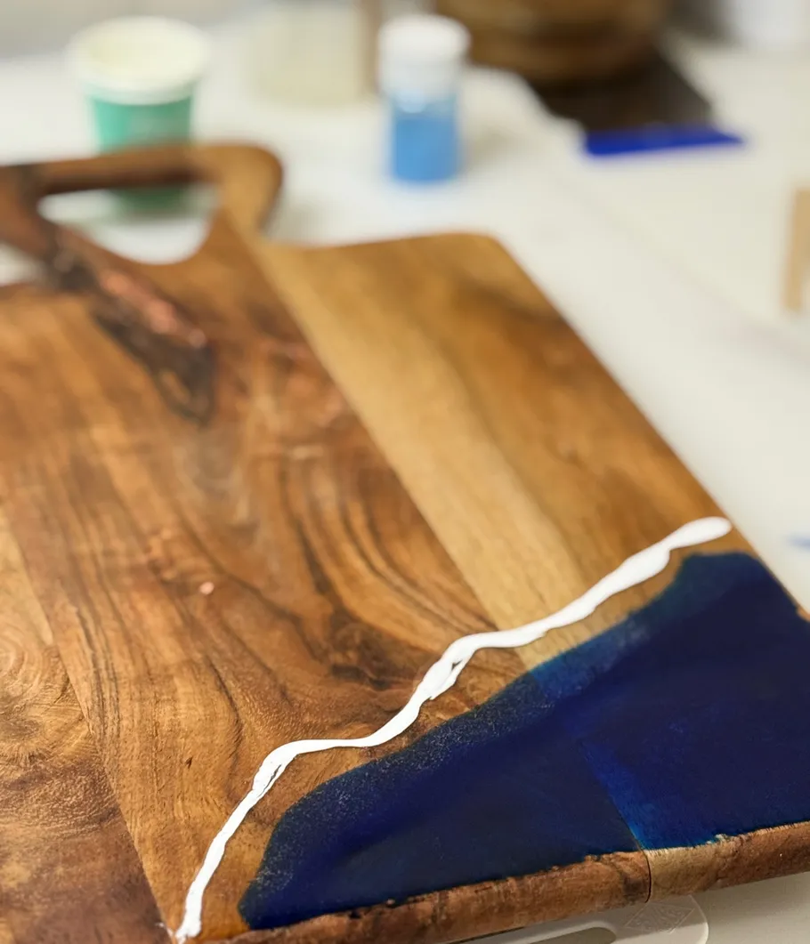 Wooden cheese board with blue epoxy design.