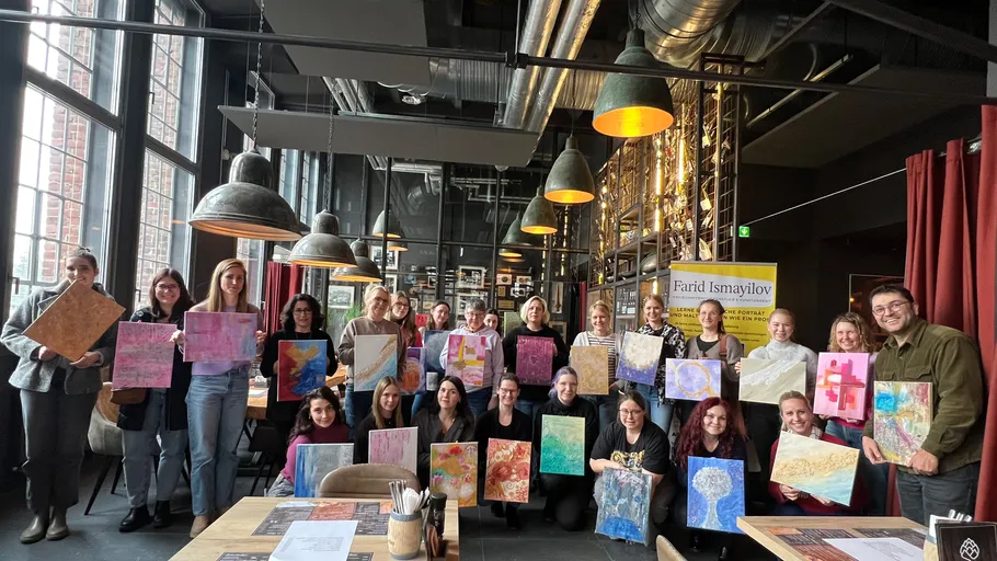 Group holding artworks in industrial-style restaurant.