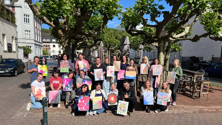 Group holding paintings on a sunny street.