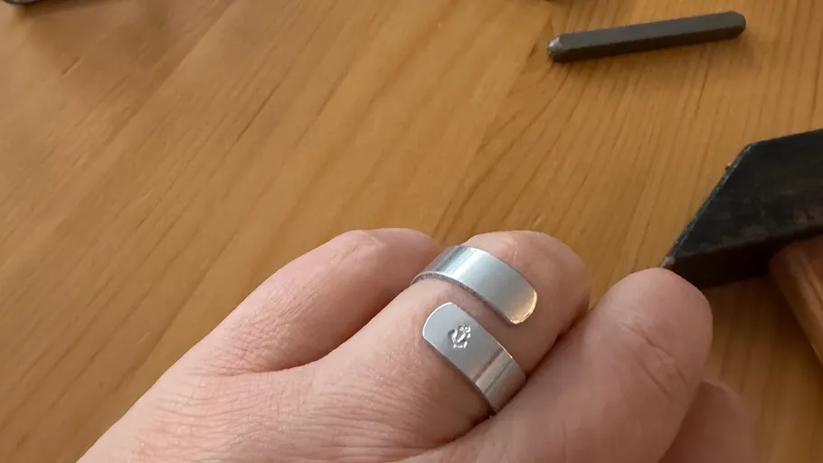 Silver ring on hand, wooden table background.