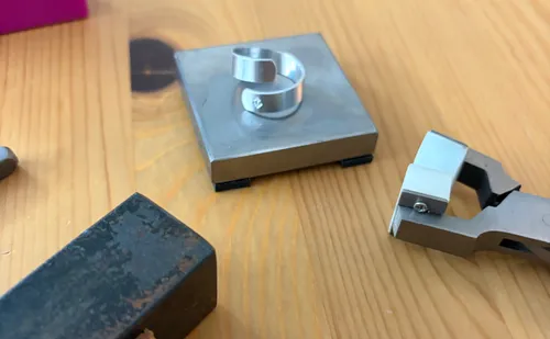 Metal tools and piece on wooden table.