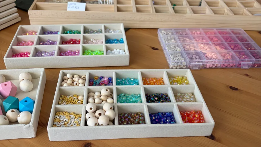 Colorful beads organized in trays on table.