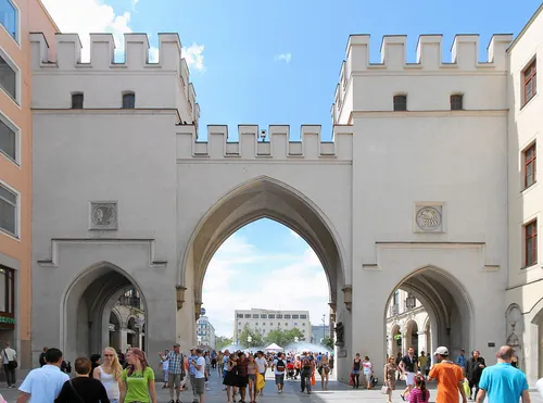 People walking through historic arched city gate.