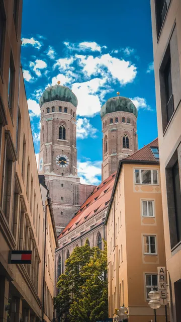 Church towers between city buildings, blue sky.