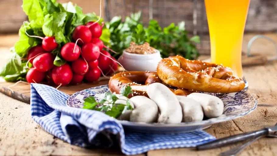 Plate with sausages, pretzel, radishes, and beer.