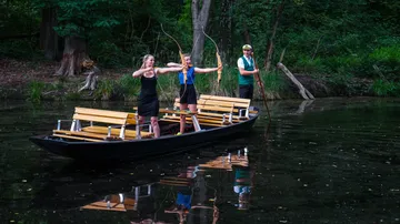 Zwei Frauen schießen Pfeile von einem Boot.