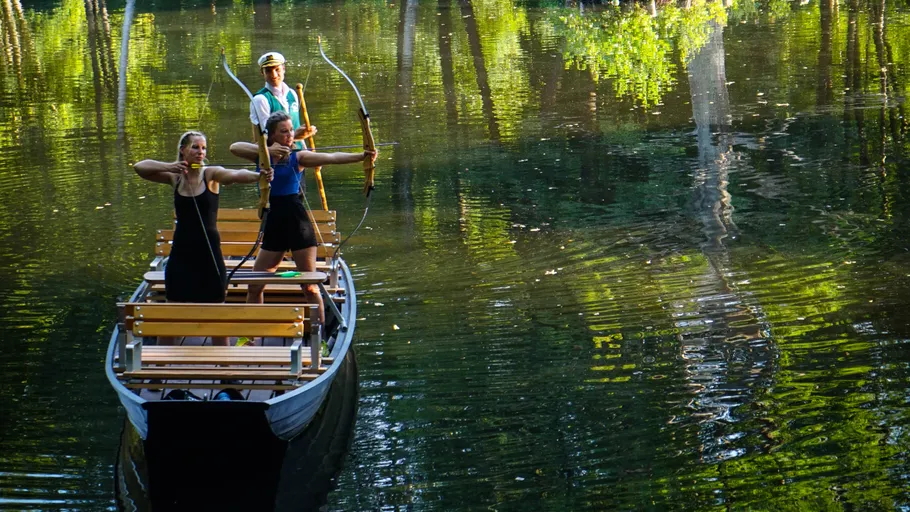 Two women practice archery on a boat.