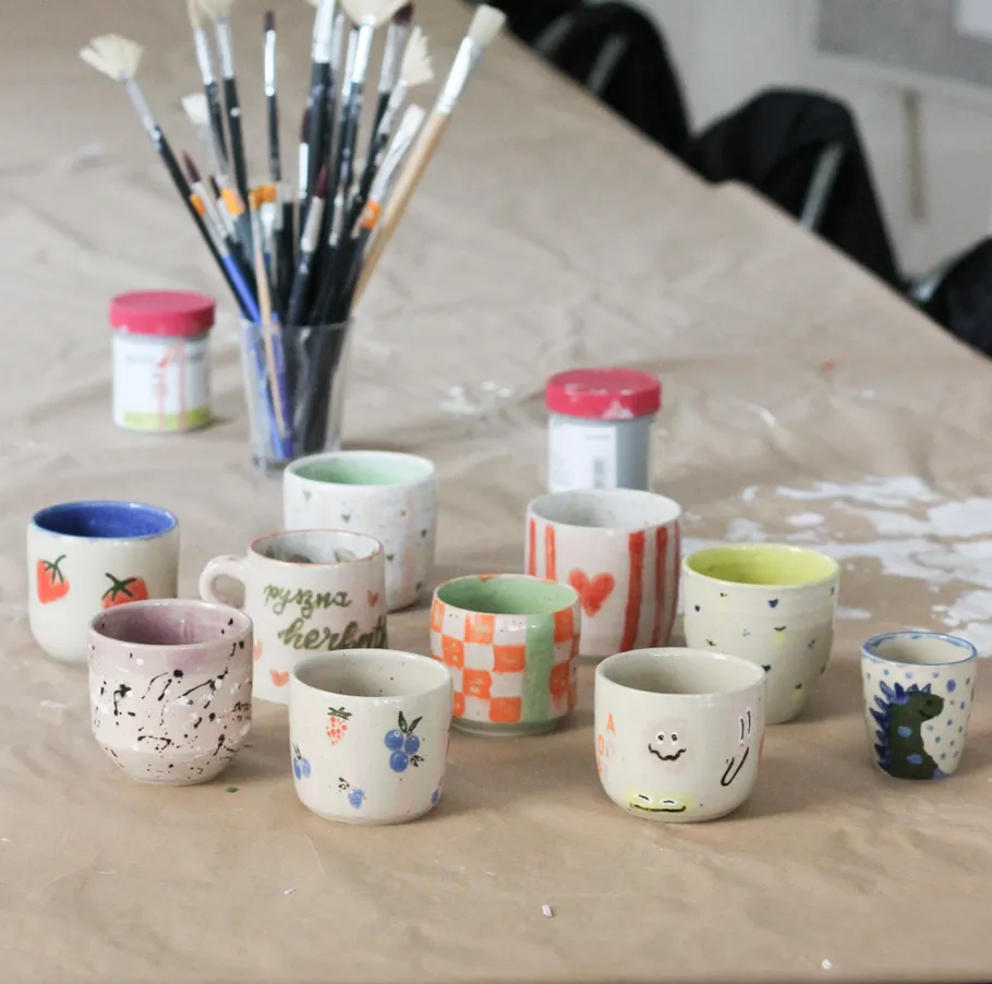 Dekorierte Tassen auf einem Tisch mit Farben.