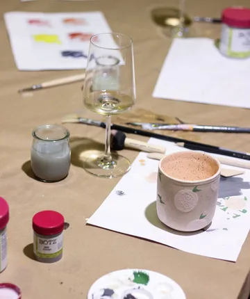 Malutensilien auf Tisch mit Weinglas.