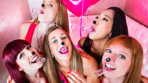 Frauen mit Spielzeugnasen und Pfeifen feiern.