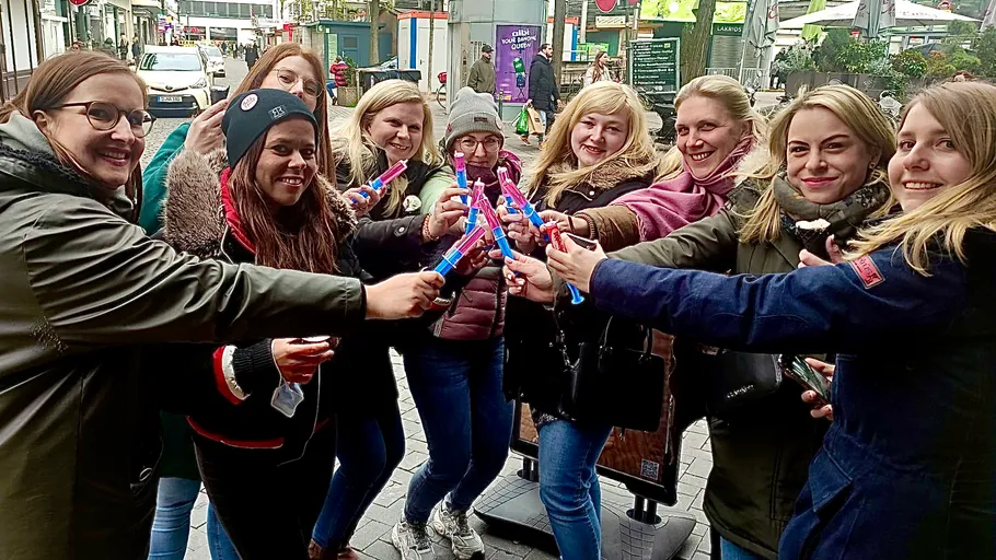 Group of women celebrating with colorful drinks outdoors.