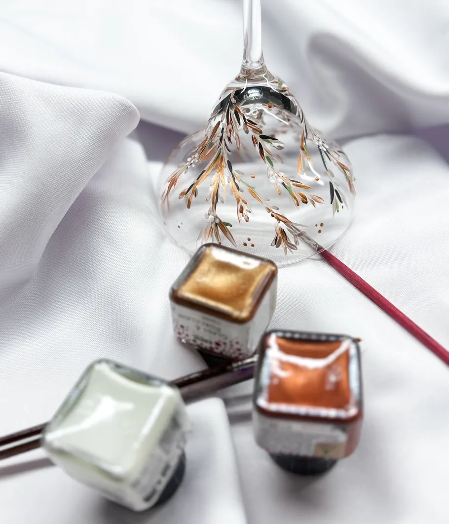 Bemaltes Glas umgeben von Farbdosen und Stoff.