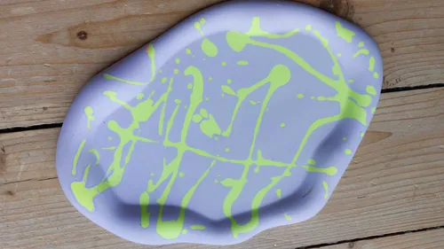 Purple ceramic plate with yellow paint splatters.