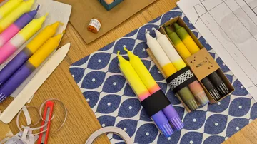 Bunte Kerzen auf einem Holztisch angeordnet.
