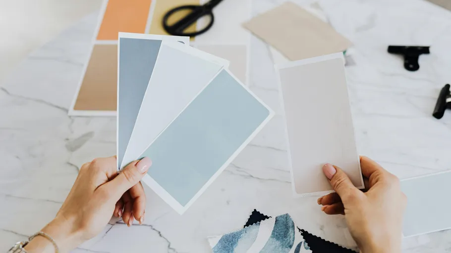 Hands holding color swatches on table.