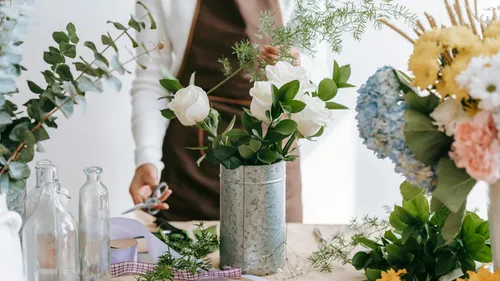 Person arranging flowers on a table.