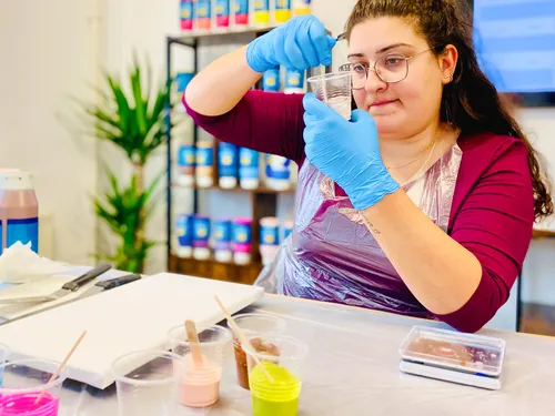 Person in apron mixes paint in studio.