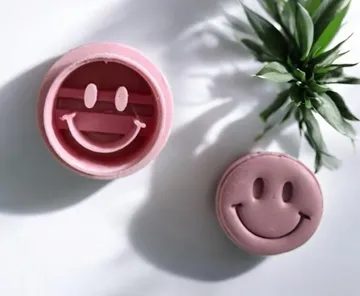 Pink smiley face stamp, plant nearby.
