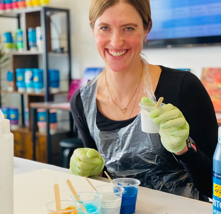 Frau lächelt, mischt Farben in einem Kunststudio.